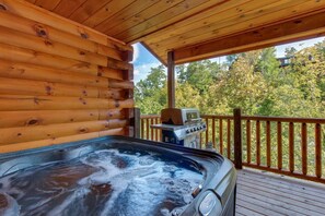 A hot tub on a wooden deck with a barbecue grill and a view of trees. - Summit View (Sevierville)
