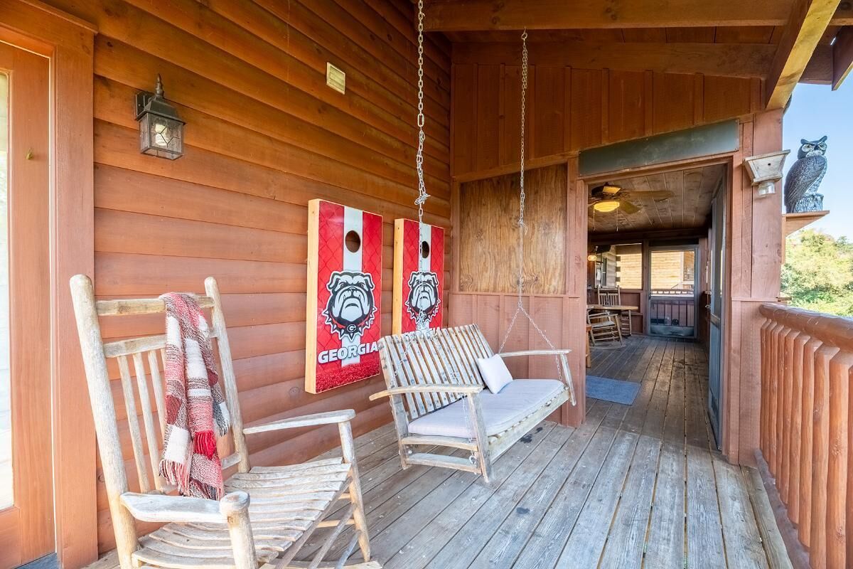 Une véranda en bois avec deux fauteuils à bascule, une lanterne suspendue et deux panneaux représentant les « Georgia Bulldogs ».