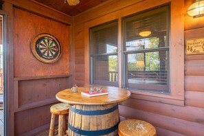 A wooden cabin interior with a dartboard, a round table with a book and glasses, and a sign reading 'The Buckner's Cabin.' - Z - Southern Style (Sevierville)