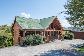 A lodge with a green metal roof, wooden exterior, and a porch with a railing. - Z - Southern Style (Sevierville)
