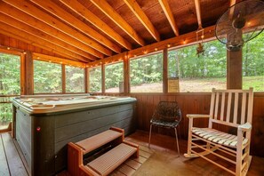 Eine Holzhütte mit Whirlpool, einem Schaukelstuhl und einem Ventilator.