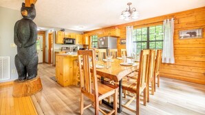A wooden cabin interior with a dining area, kitchen, and a bear statue. - Z - Lone Wolf (Sevierville)