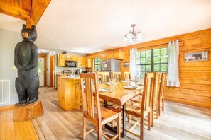 Ein Holzblockhaus-Innenraum mit Essbereich, Küche und einer Bärenstatue.