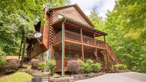 A log cabin with a balcony, surrounded by greenery. - Z - Lone Wolf (Sevierville)