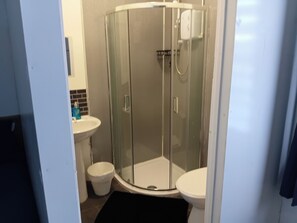 A bathroom with a glass-enclosed shower, a white sink, and a toilet. - Studio Sleeps 2 With Parking (Oldbury)
