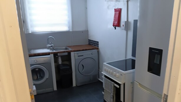 A compact kitchen with a washing machine, a sink, and a built-in oven.
