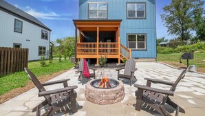 Ein zweistöckiges Haus mit Holzterrasse und Feuerstelle im Garten.