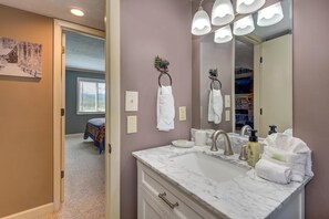 A bathroom with a marble sink, a large mirror, and a towel rack. - Teetop Getaway (Gatlinburg)