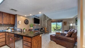 A spacious kitchen with a central island, wooden cabinets, and a built-in dishwasher. - Teetop Getaway (Gatlinburg)