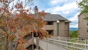A multi-story building with a balcony, a staircase, and a view of the surrounding landscape. - Teetop Getaway (Gatlinburg)