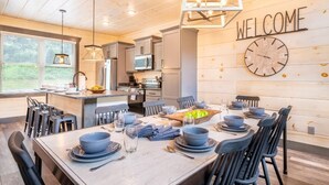 Una cocina moderna con un cartel que dice 'WELCOME', un comedor con una mesa de madera dispuesta para cuatro personas y vistas al exterior.
