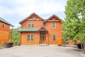 A two-story log cabin with a green roof, a front porch, and a sign indicating it is a lodge. - Autumn Bear (Sevierville)