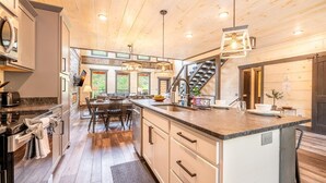 Una cocina moderna con una isla central, electrodomésticos integrados y una escalera que lleva a un nivel superior.