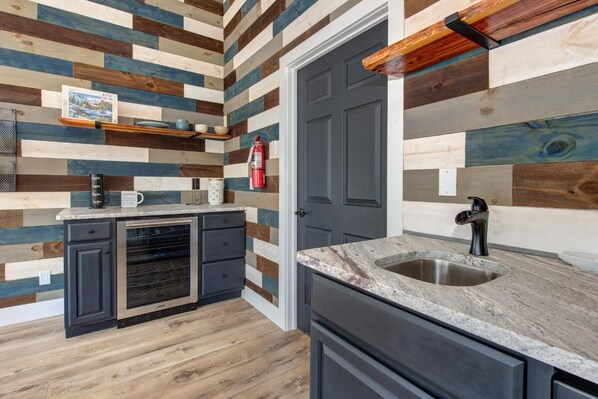 A kitchen with a wooden plank wall, a built-in oven, and a stainless steel sink. - Z - Bear Pause Retreat (Sevierville)