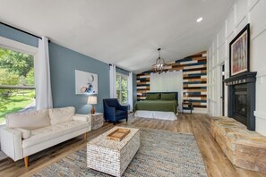 A bedroom with a bed, a nightstand, a chair, a sofa, and a fireplace. - Z - Bear Pause Retreat (Sevierville)