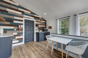 A kitchen with a wooden plank wall, a gray door, a white table, and two white chairs. - Z - Bear Pause Retreat (Sevierville)