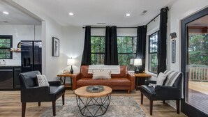 Una sala de estar con sofá, dos sillones, una mesa de centro y vistas a una terraza.