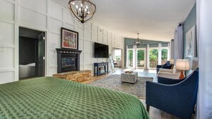 Un dormitorio amplio con una cama grande, chimenea, televisor y vistas al exterior.