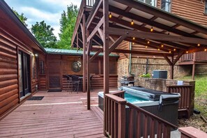 A wooden cabin with a deck, outdoor seating, a hot tub, and a stone wall. - Z - Bear Pause Retreat (Sevierville)