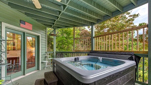 Un espacio al aire libre cubierto con un jacuzzi, una terraza de madera y vistas a árboles.