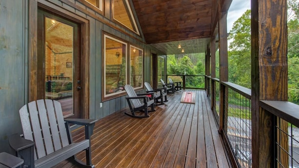 A wooden deck with Adirondack chairs and a table, overlooking a natural landscape. - Dreamcatcher Lodge (Sevierville)