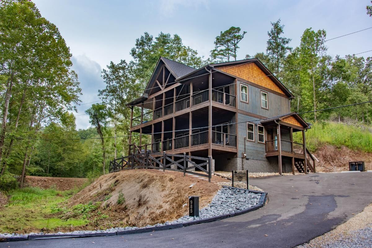 A multi-story wooden house with a balcony, surrounded by trees.