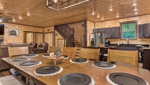 A wooden dining room with a long table set for six, surrounded by chairs. - Dreamcatcher Lodge (Sevierville)