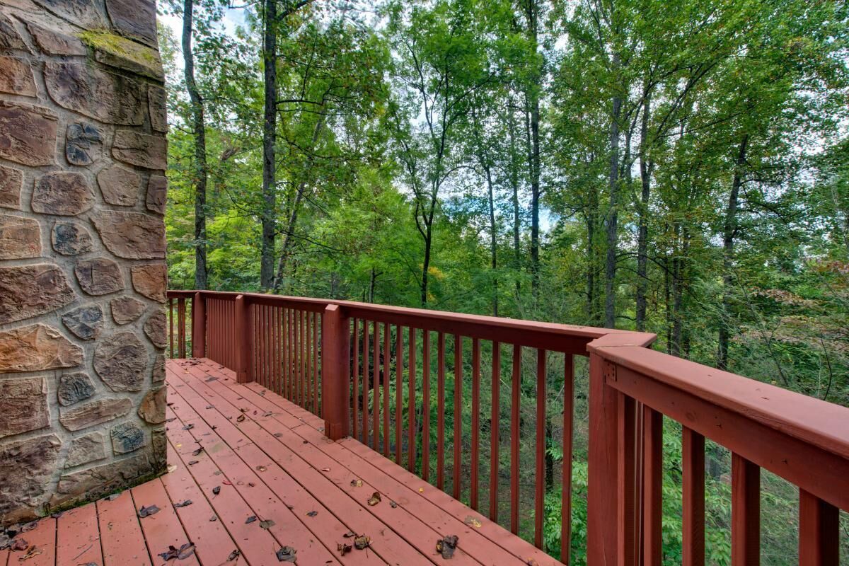 A stone wall, a red wooden deck, and a forested background.