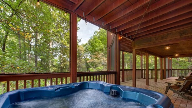 A hot tub on a wooden deck with a view of trees. - Sage Grass Retreat (Sevierville)