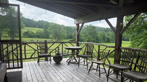 Een houten terras met rustieke stoelen en een tafel, met uitzicht op een groen landschap.
