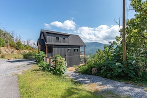 A two-story house with a dark exterior, a gravel driveway, and a view of mountains. - Black Bear-y Ridge (Sevierville)