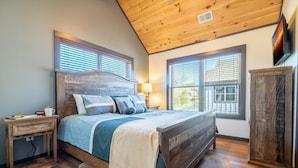 A bedroom with a wooden headboard, a bedside table, a lamp, and a wardrobe. - Hochatime (Sevierville)