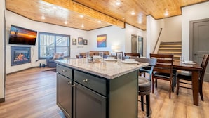 A modern kitchen with a wooden ceiling, a dining area with a table and chairs, and a fireplace. - Hochatime (Sevierville)