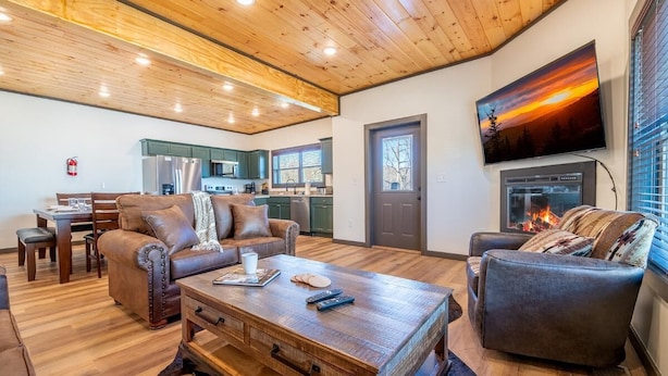 A spacious living area with a fireplace, a television mounted on the wall, and a dining area with a table and chairs. - Hochatime (Sevierville)