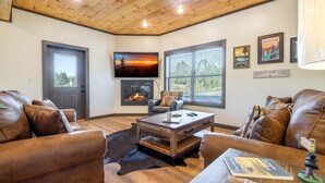 A living room with leather sofas, a wooden coffee table, a fireplace, and framed artwork on the walls. - Hochatime (Sevierville)