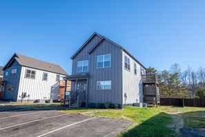 A two-story building with a grey exterior, a front entrance with a staircase, and a parking lot in front. - Hochatime (Sevierville)