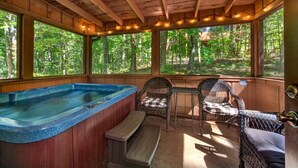 A wooden cabin with a hot tub, wicker chairs, and a view of the forest. - Whistling Woods Hideaway (Sevierville)