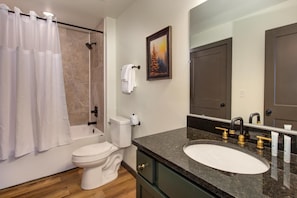 A bathroom with a bathtub, toilet, sink, and a painting on the wall. - Blue Bella (Sevierville)