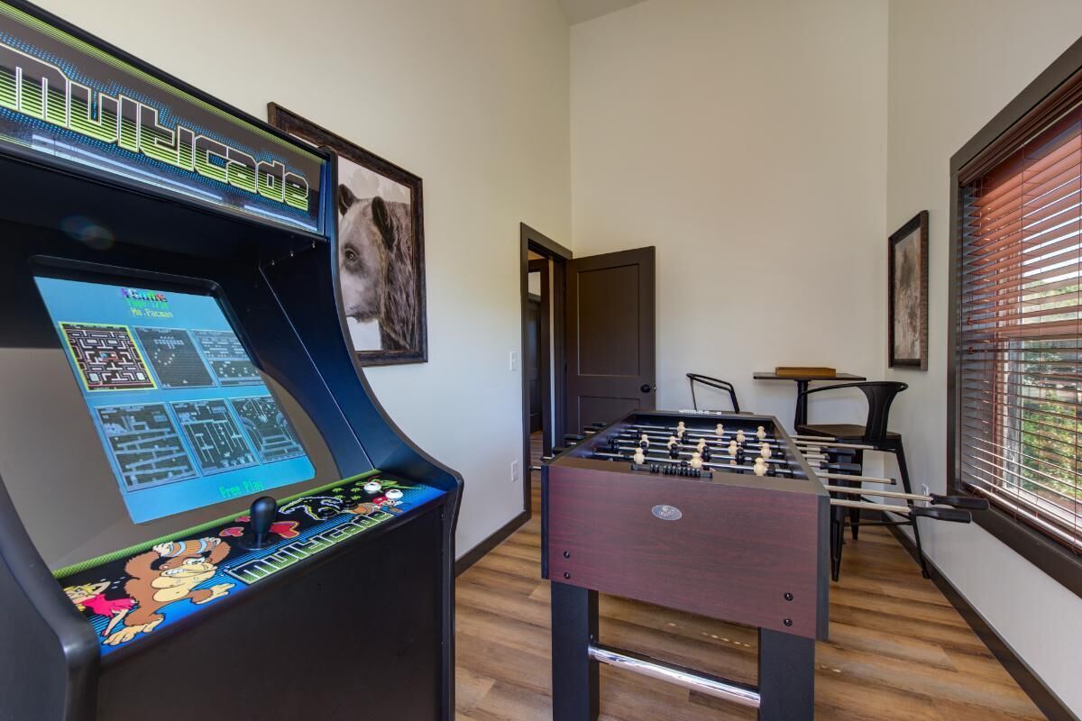 Ein Zimmer mit einer Fußballtischkickeranlage, einer Bedieneinheit für den Kicker und einem gerahmten Bild an der Wand.