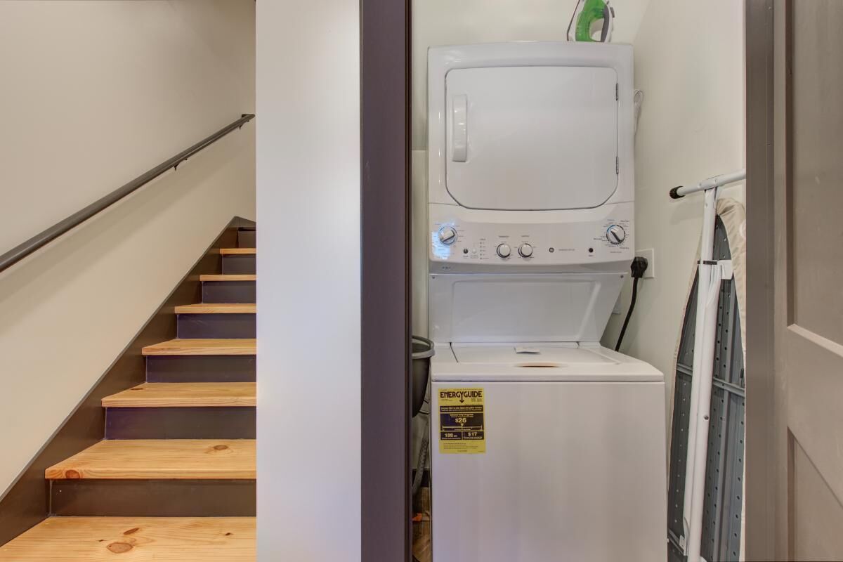Ein Waschraum mit Waschmaschine, Trockner und einer Treppe zu einer anderen Etage.