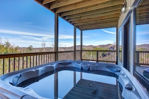 Ein Whirlpool auf einer Holzterrasse mit Blick auf die Landschaft.
