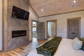 Ein Schlafzimmer mit Kamin, einem Bett mit Felldecke und einem an der Wand befestigten Fernseher.