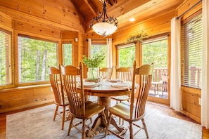 A wooden interior with a round dining table, four chairs, and a chandelier. - Smoky Breeze Retreat (Sevierville)