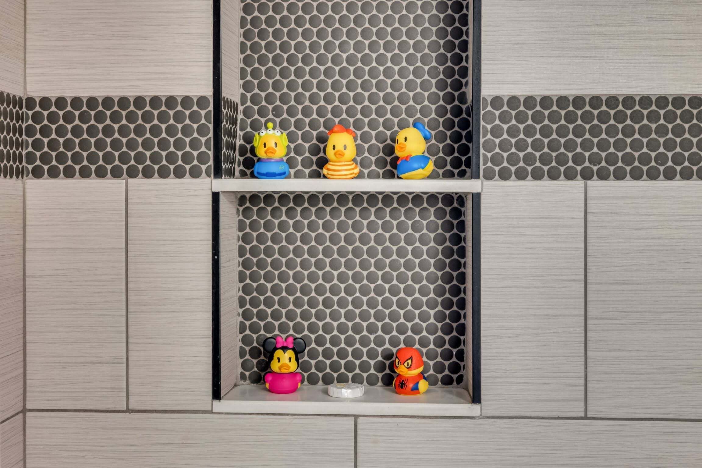 Une étagère avec des canards en caoutchouc et une figurine de Mickey Mouse.