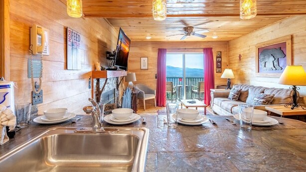 A wooden interior with a kitchen, dining area, and a balcony with a view. - Z - Black Bear Hideout (Gatlinburg)