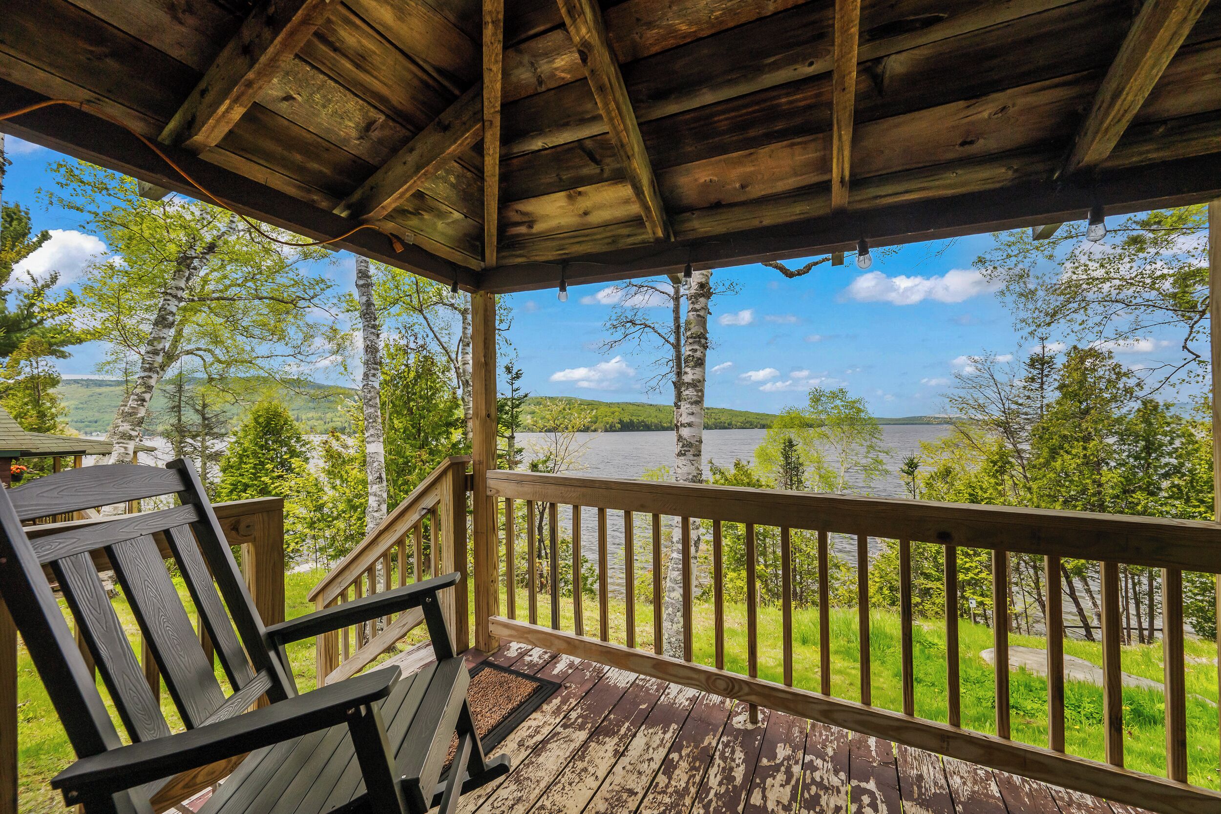 A wooden deck with a view of a lake and trees.
