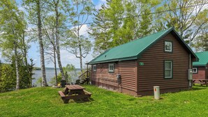 A cabin with a green roof, a fire pit, and a picnic table. - NEW LISTING SPECIAL! Rangeley Lake | Shared Dock | Pet Friendly (Rangeley)