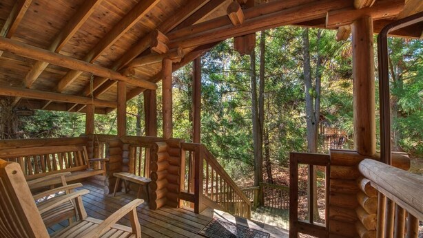 A wooden log cabin with a porch, benches, and a staircase leading to a deck. - Unforgettable Dreams (Sevierville)