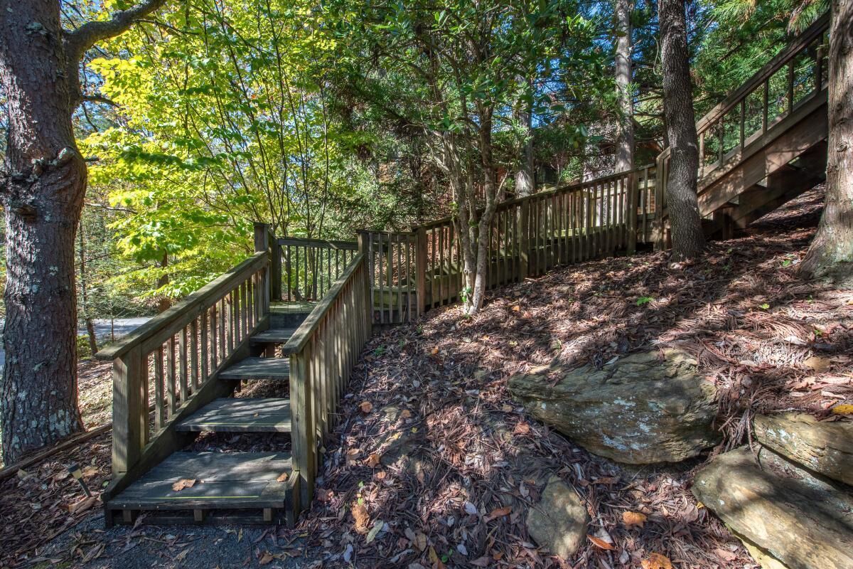 A wooden staircase leading up a forested hill, surrounded by trees and natural ground cover.