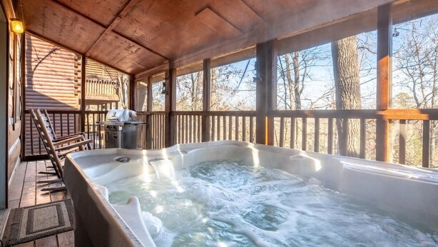 A hot tub in a wooden deck area with a view of trees. - Antlers Haven (Pigeon Forge)